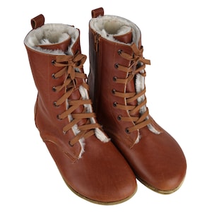 May include: A pair of brown leather boots with white fur lining and lace-up fastenings.