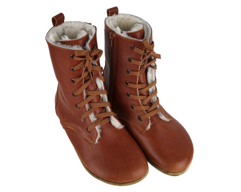May include: A pair of brown leather boots with white fur lining and lace-up fastenings.