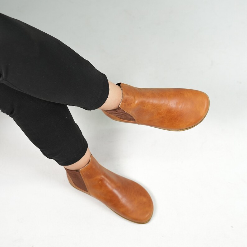 May include: A pair of brown leather ankle boots with a pull-on design. The boots have a rounded toe and a low heel.