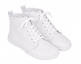 May include: A pair of solid white ankle-high boots featuring a smooth finish, rounded toes, and matching white laces threaded through silver-toned metal eyelets. Each boot includes a small pull tab at the heel and a flat, tonal white rubber sole.