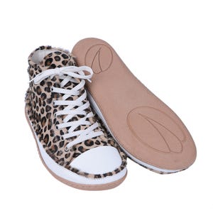May include: Leopard print high-top sneakers with white laces and a white toe cap. The shoes have a brown suede sole.
