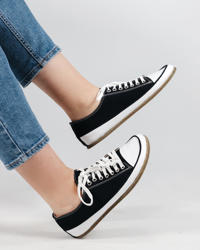 May include: A pair of black canvas low-top sneakers with white soles and white laces.