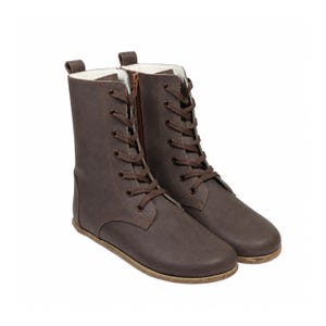 May include: A pair of mid-calf brown boots featuring a lace-up front with dark brown laces, metal eyelets, and a side zipper closure. The boots have a rounded toe, a flat sole, and a light-colored interior lining visible at the top collar.