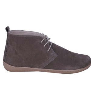 May include: A pair of gray suede ankle boots with a lace-up closure and a light brown rubber sole.