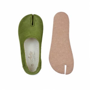 May include: Olive green split-toe shoe with a matching insole. The shoe features a unique design with a separate space for the big toe. The insole is a light tan color. The shoe is labeled with the brand name "Antao".