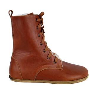 May include: Brown leather lace-up boots with a white fur lining. The boots have a rounded toe and a flat sole.