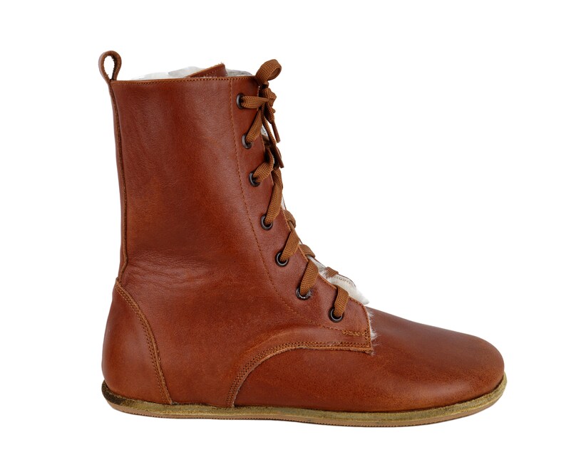 May include: Brown leather lace-up boots with a white fur lining. The boots have a rounded toe and a flat sole.