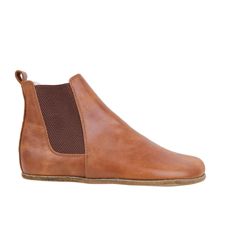 May include: Brown leather ankle boots with a pull-on design and elastic side panels.