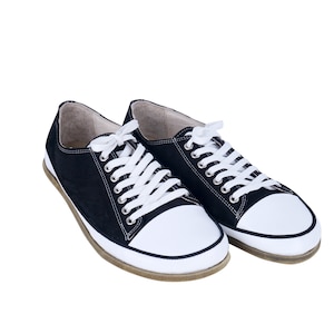 May include: A pair of black canvas low top sneakers with white laces and white rubber soles.
