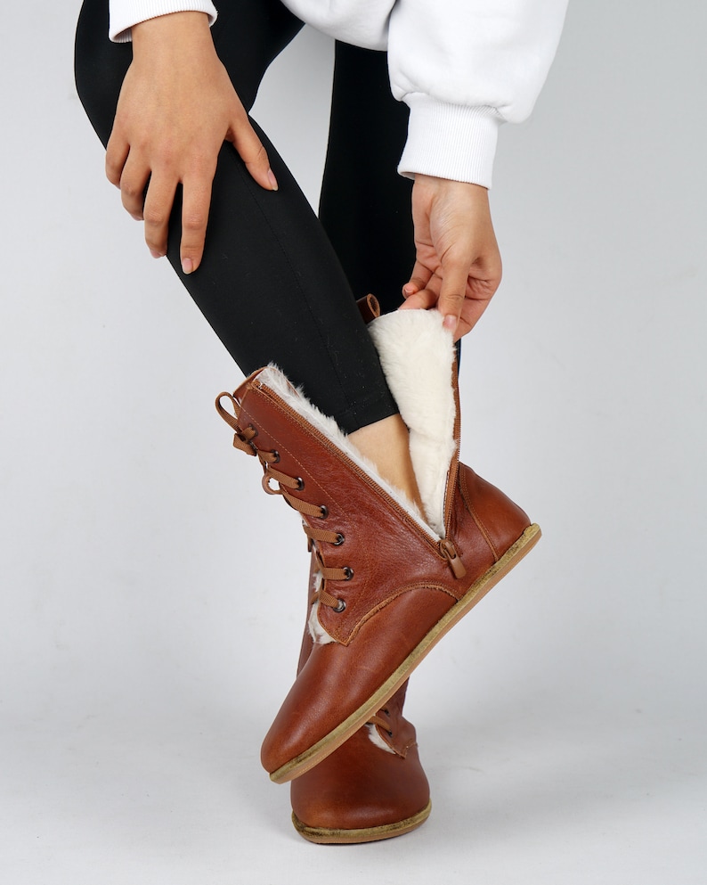May include: Brown leather boots with a zip and laces. The boots have a white faux fur lining.