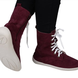 May include: Burgundy suede lace-up boots with white laces and a white rubber sole.
