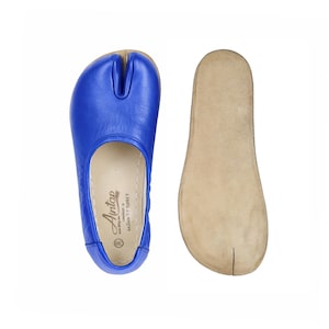 May include: A pair of blue split-toe shoes with a matching insole. The shoes are made of leather and have a unique design. The insole is a light tan colour. The shoes are size 38.
