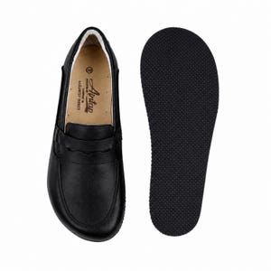 May include: A pair of black leather loafers with a smooth finish and a classic penny strap across the vamp. The interior features a tan insole with the text Aintap, size 39, and Gaziantep Turkey. The separate black outsole has a textured grip.