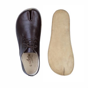 May include: Brown leather split-toe shoes with laces, next to a matching insole. The shoes have a unique design with a separate section for the big toe. The insole is a light tan colour. The shoes are a size 42.
