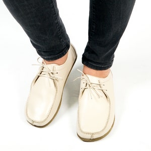 May include: A pair of off-white leather lace-up shoes with a rounded toe and a thick sole.