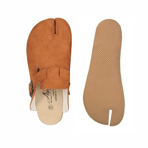 May include: A pair of brown split-toe clogs with a buckle strap and a separate sole. The clogs are made of suede-like material. The sole is a light brown color. The clogs are size 38.
