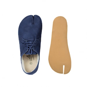 May include: Navy blue split-toe shoe with laces, next to a tan insole. The shoe has a unique design with a separate space for the big toe. The insole is a matching shape. The shoe has the number 38 on the insole.