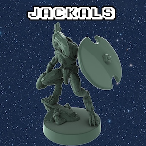 Può includere: Una statuetta in miniatura di plastica verde di un guerriero Jackal che tiene uno scudo. La statuetta è in piedi su una base circolare.
