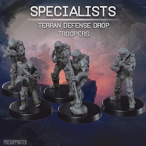 May include: A set of five grey miniature soldier figurines titled SPECIALISTS TERRAN DEFENSE DROP TROOPERS. Each figure wears tactical armour, helmets, and carries various rifles or heavy weaponry, standing on individual black circular bases.