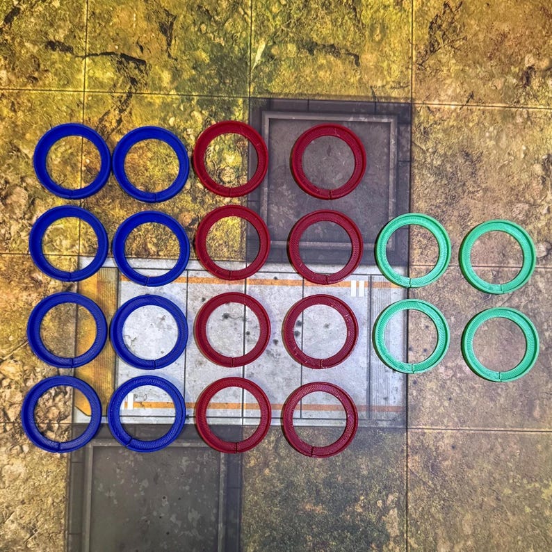 May include: A collection of 18 round tokens in three colours: blue, red, and green. The tokens are arranged in a grid pattern on a textured surface.