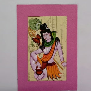Puede incluir: Una pintura colorida de una deidad hind&uacute;, enmarcada en rosa. La obra representa una figura sentada con un tridente, vestida con ropas naranjas y amarillas, y una serpiente alrededor del cuello. El fondo parece ser papel envejecido.