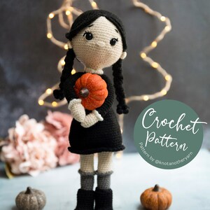 Op de afbeelding: Haakpatroon voor een pop met zwart haar, een zwarte jurk en een pompoen. De pop houdt de pompoen in haar handen. Het patroon is van @knotanotheryarn. #knotanotheryarn