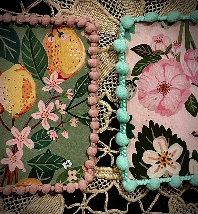 May include: Two square fabric panels with a decorative trim of pink and blue pom-poms. The panels feature floral and fruit patterns on a green and pink background.