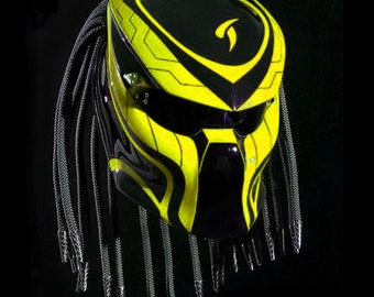 May include: A black and yellow motorcycle helmet with a predator-style design and black dreadlocks.