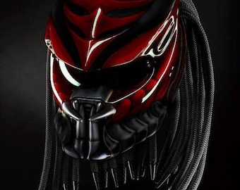 May include: A red and black motorcycle helmet with a black braided beard. The helmet has a sleek, futuristic design with a black visor.