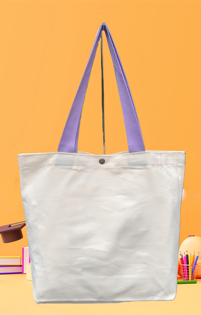 May include: A white tote bag with lavender-colored handles. The bag has a button closure and is made of a sturdy material. The tote bag is suitable for carrying books, groceries, or other items. The background is a solid orange color.