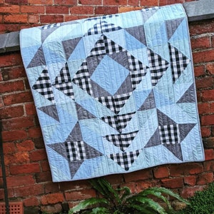 May include: A blue and white quilt with a geometric pattern. The quilt is made of squares and triangles, and it has a checkered design.