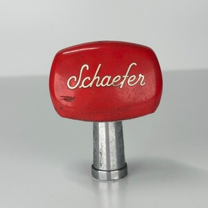 May include: Red metal beer tap handle with the word "Schaefer" in white lettering.