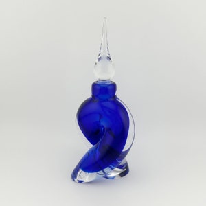 May include: A cobalt blue glass bottle with a clear glass stopper. The bottle is shaped like a swirl or a knot.