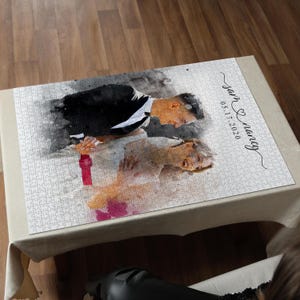 May include: A completed jigsaw puzzle featuring a watercolor image of a couple in formal attire. The puzzle includes the names "Sam & Nancy" and the date "05.17.2020" in elegant script. The puzzle is set on a neutral-toned surface.