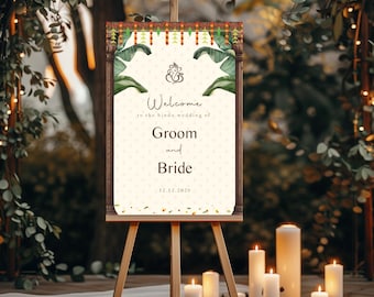 May include: A wooden easel displaying a welcome sign for a Hindu wedding. The sign features the words "Welcome Groom and Bride" with decorative elements of green leaves and traditional Indian patterns. The date 12.12.2026 is also displayed.