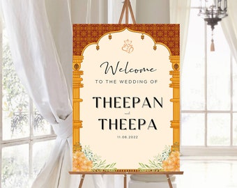 May include: Welcome to the wedding of Theepan and Theepa, a wedding sign with a gold and red archway design and floral accents. The date 11.06.2022 is printed below the names.