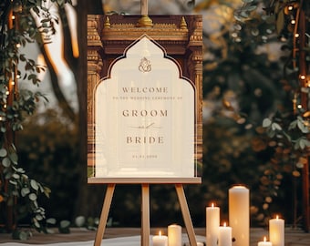 May include: A wooden easel displaying a wedding welcome sign. The sign features ornate architectural details and the words "Welcome to the Wedding Ceremony of Groom and Bride." The sign is surrounded by candles.
