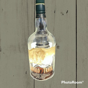 May include: A clear glass bottle with a black cord hanging from the top. The bottle is labeled "Buffalo Trace Kentucky Straight Bourbon Whiskey".