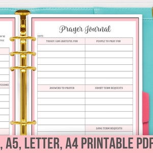May include: A printable prayer journal and gratitude journal with pink and white pages. The journals are bound together with gold rings. The text on the cover of the prayer journal reads "Prayer Journal". The text on the cover of the gratitude journal reads "Gratitude".