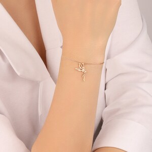 Puede incluir: Un delicado brazalete de oro con un dije de hada. El brazalete est&aacute; hecho de una cadena fina y el dije de hada es detallado e intrincado.