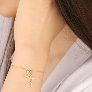 Puede incluir: Un brazalete de cadena dorada con un delicado encanto de hada. El hada est&aacute; representada en posici&oacute;n sentada con las alas extendidas.