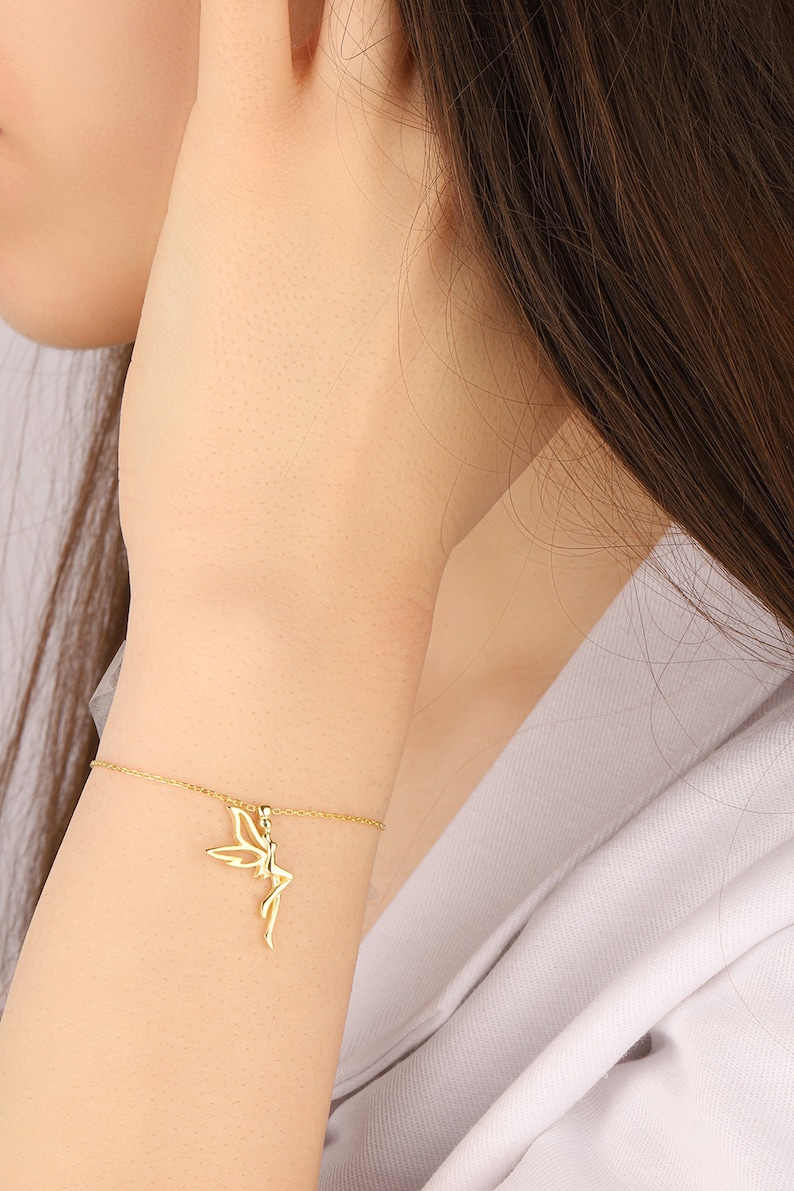 Puede incluir: Un brazalete de cadena dorada con un delicado encanto de hada. El hada est&aacute; representada en posici&oacute;n sentada con las alas extendidas.