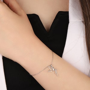 Puede incluir: Un brazalete de cadena de plata con un delicado encanto de hada. El hada est&aacute; representada con las alas extendidas y un vestido fluido.