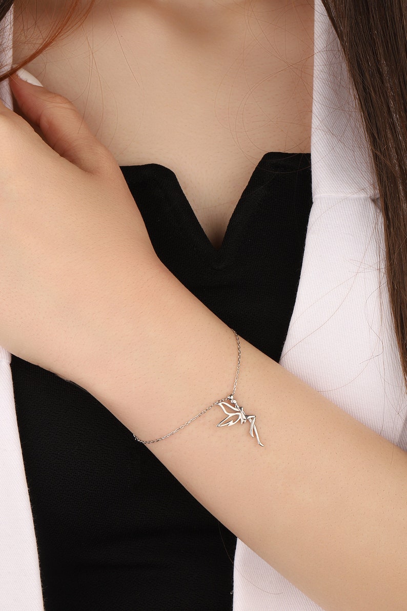 Puede incluir: Un brazalete de cadena de plata con un delicado encanto de hada. El hada est&aacute; representada con las alas extendidas y un vestido fluido.