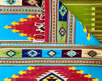 May include: A colorful woven rug with geometric patterns in shades of red, blue, yellow, green, and brown. The rug has a fringed edge and is folded in half.