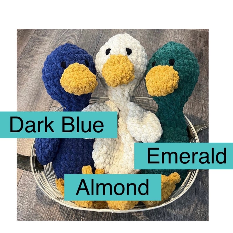 May include: Three crocheted duck plushies in a wire basket. The ducks are dark blue, white, and green. The ducks have yellow beaks and feet.
