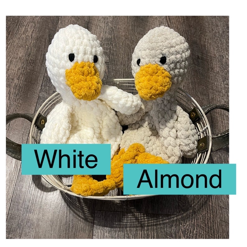May include: Two crocheted plush duck toys in a wire basket. One duck is white and the other is almond colored. Both ducks have yellow beaks and feet.