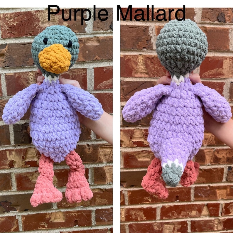 May include: Purple crocheted mallard duck plush toy with a green head and orange beak. The duck has pink legs and a white stripe around its neck.
