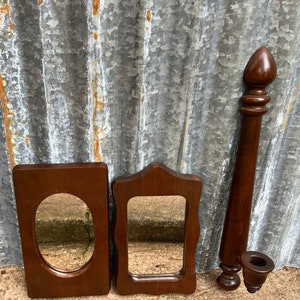 May include: Three wooden framed mirrors, one oval and two rectangular, with a wooden decorative piece with a rounded top.