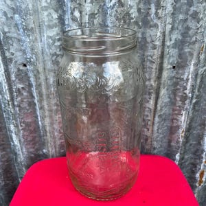May include: A clear glass jar with a threaded neck for a lid. The glass features embossed text that reads Vlasic and includes the measurement 32 oz. The jar has a cylindrical body with a wide mouth and a smooth, transparent finish throughout the glass.